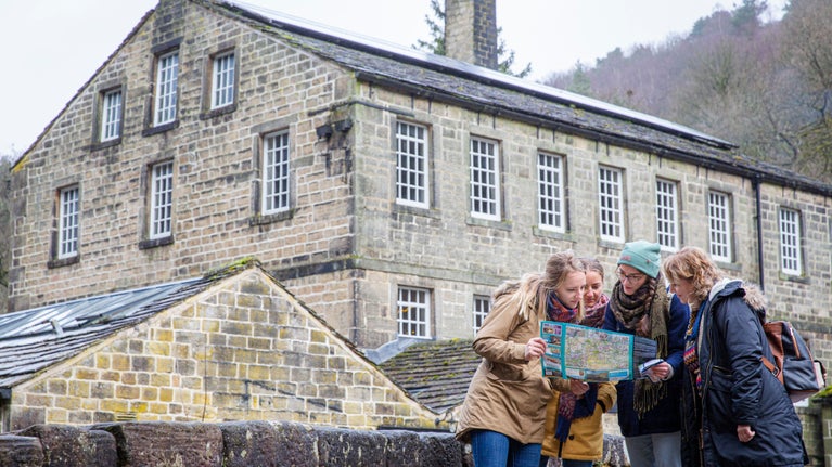 A group reading a map in front of the 18th century cotton mill